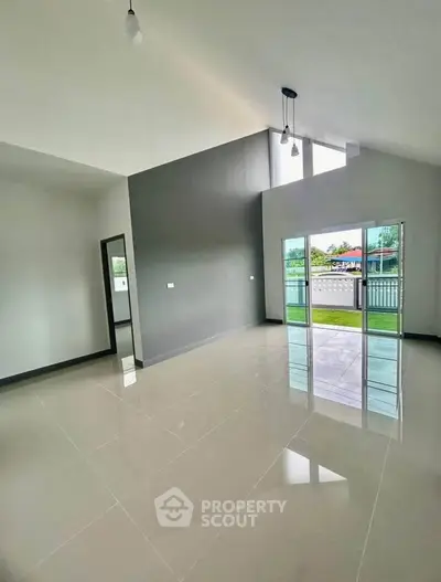 Spacious modern living room with high ceilings and large windows offering natural light and outdoor views.