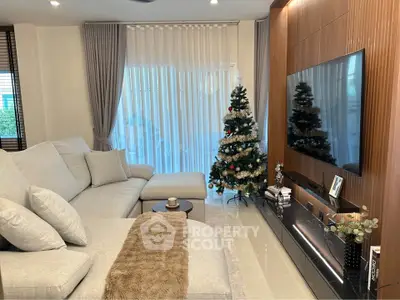 Luxurious living room with modern decor and Christmas tree, featuring a large sectional sofa and flat-screen TV.