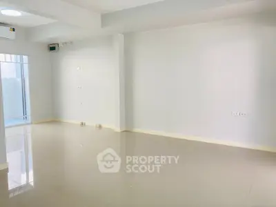 Spacious and well-lit empty room with glossy tiled flooring and ample wall sockets, perfect for a customizable living space.