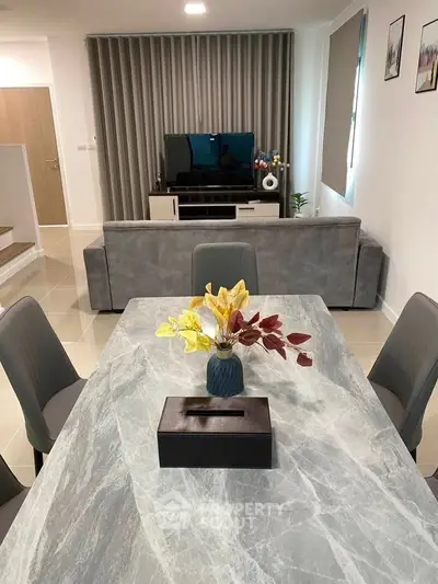 Modern living room with stylish decor and open layout, featuring a sleek dining table and comfortable seating.