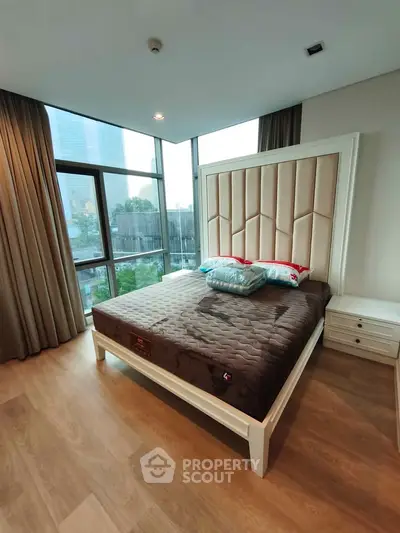 Luxurious bedroom with floor-to-ceiling windows and city view, featuring elegant decor and modern furnishings.