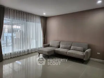 Spacious living room with modern sofa and large window offering natural light.