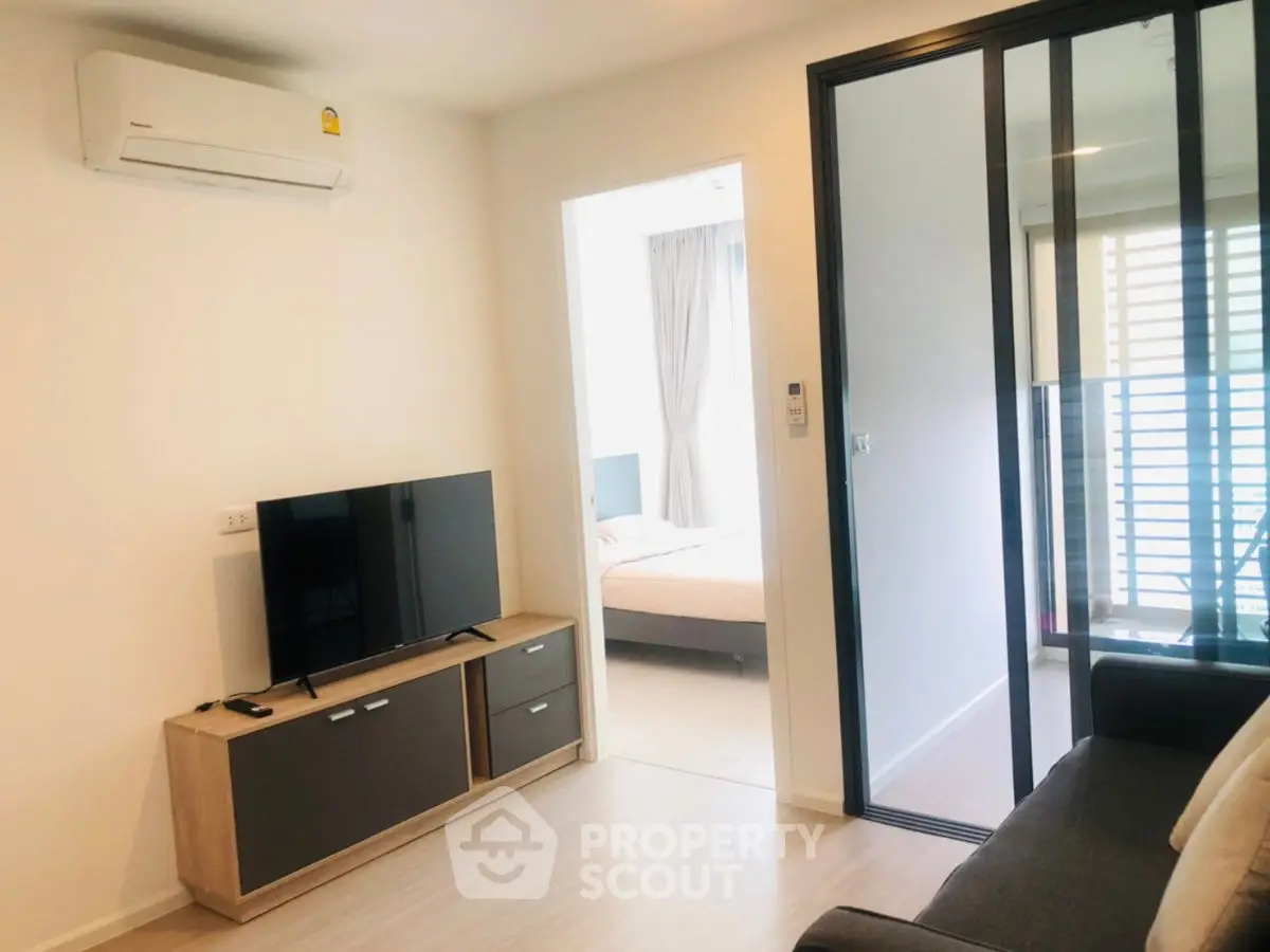 Modern living room with TV and air conditioning, adjacent to a cozy bedroom.