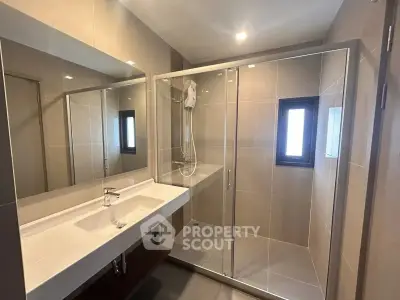 Modern bathroom with glass shower and sleek vanity in a contemporary home.
