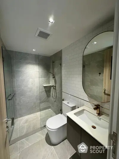 Modern bathroom with sleek design, featuring glass shower enclosure and elegant fixtures.