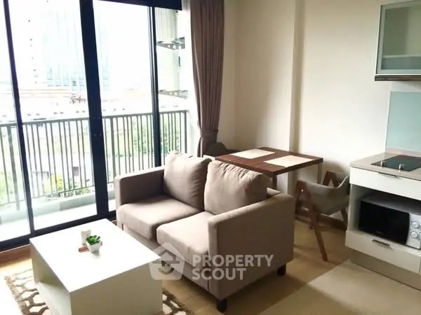 Modern living room with cozy sofa and dining area, featuring large windows and balcony access.