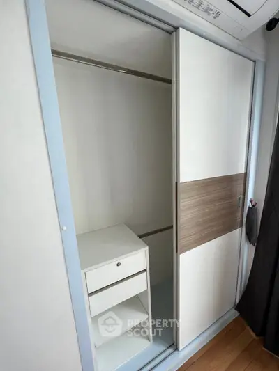 Spacious built-in wardrobe with sliding doors and storage drawers in modern apartment.