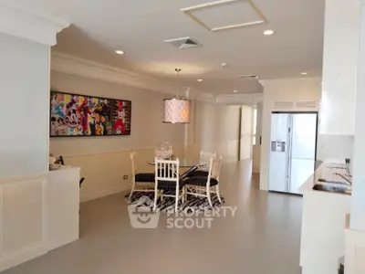 Spacious dining area with modern decor and large refrigerator in open layout apartment.