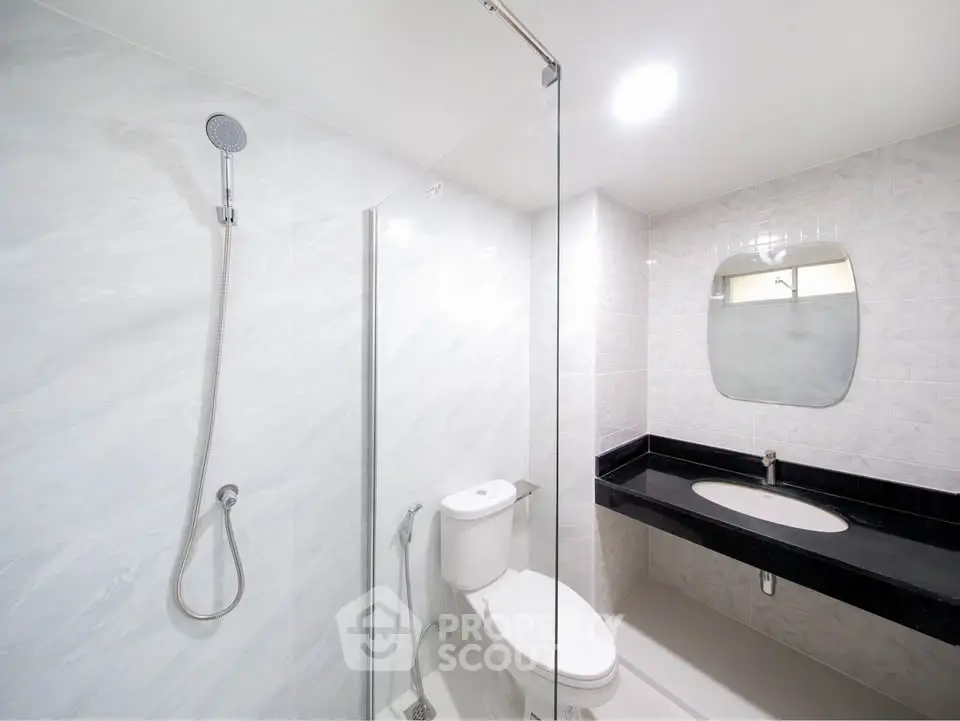 Modern bathroom with sleek design, featuring a glass shower and elegant black countertop.