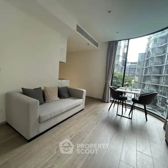 Modern living room with large windows and dining area in urban apartment.