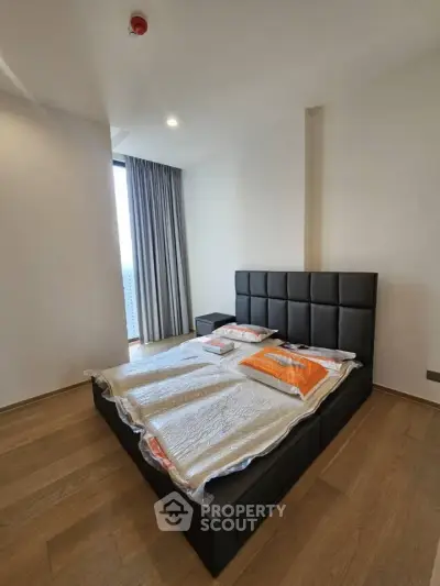 Modern bedroom with stylish bed and wooden flooring in a high-rise apartment.