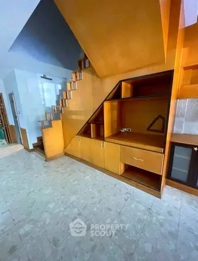 Spacious living area with unique wooden staircase and built-in storage, perfect for modern living.