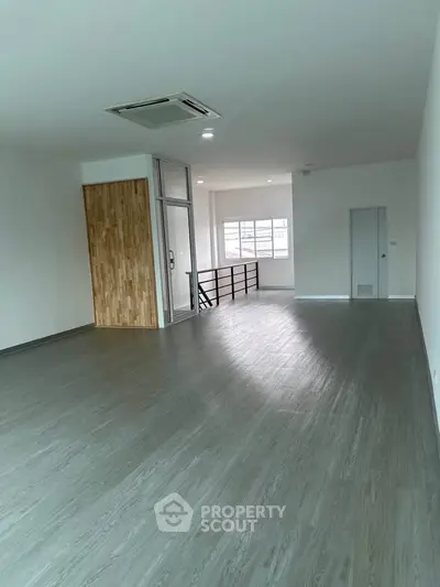 Spacious modern living room with sleek flooring and large windows for natural light.