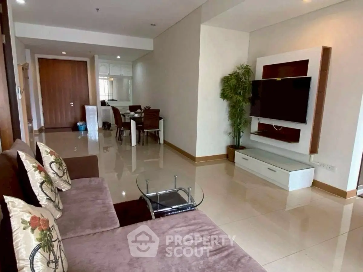Spacious living room with modern decor and wall-mounted TV in a stylish apartment.
