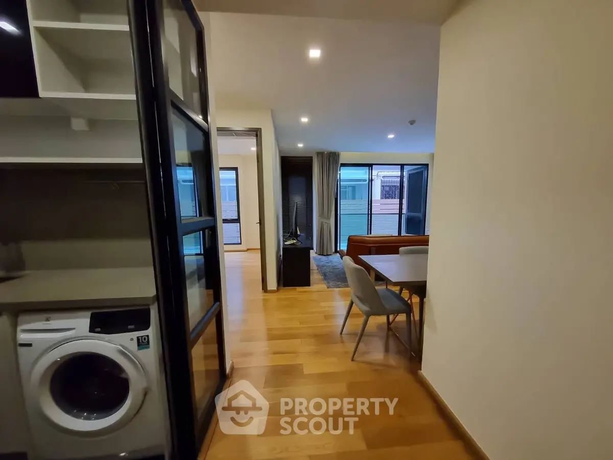 Modern apartment interior with open layout, featuring a washing machine and stylish dining area.