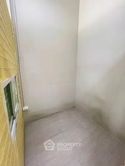 Compact storage room with tiled floor and yellow brick wall, ideal for organizing.