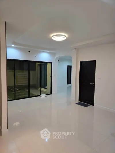 Spacious modern living room with sleek design and large glass doors leading to outdoor area.