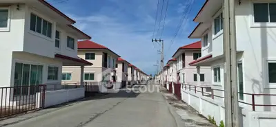 Charming suburban street lined with modern two-story homes featuring red roofs and white facades.