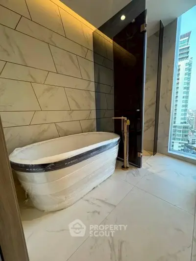 Luxurious bathroom with marble tiles and a freestanding bathtub offering a city view.