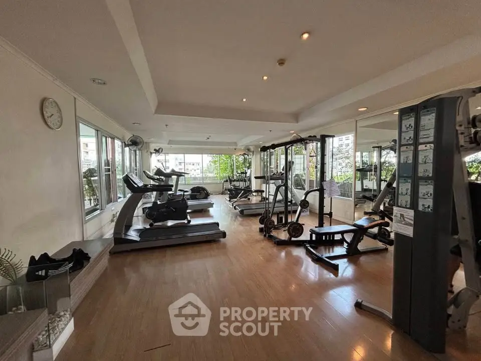 Spacious gym with modern equipment and large windows offering a bright workout environment.