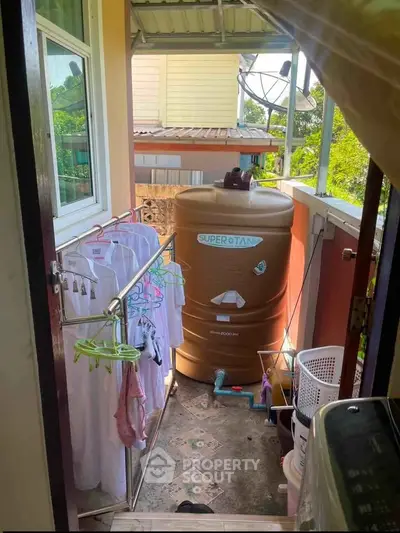Compact balcony with water tank and laundry area in urban home