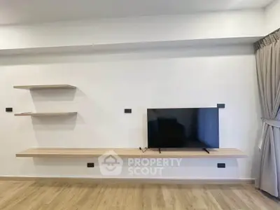 Modern living room with sleek TV setup and floating shelves on a wooden floor.