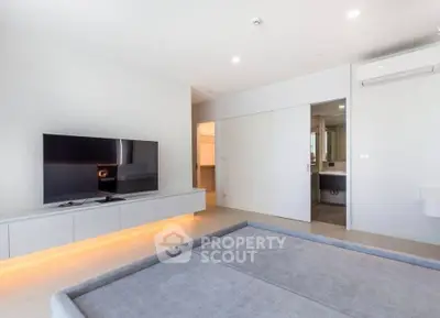 Modern living room with sleek TV setup and ambient lighting, showcasing minimalist design and spacious layout.