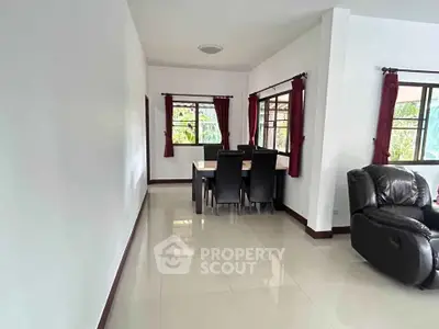 Spacious living room with dining area and large windows, featuring modern furniture and natural light.