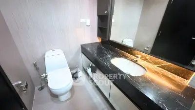 Modern bathroom with sleek black marble countertop and elegant fixtures.