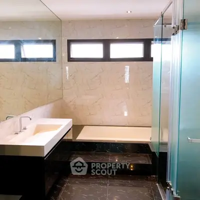 Luxurious modern bathroom with marble tiles and sleek glass shower enclosure.
