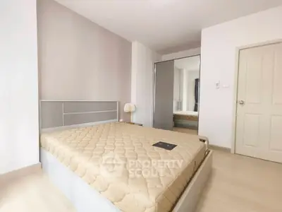Spacious bedroom with modern design and ample natural light, featuring a comfortable bed and sleek mirrored wardrobe.