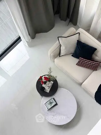 Modern living room with stylish sofa and elegant coffee tables, featuring a chic decor and bright ambiance.