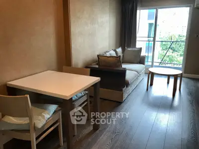 Modern living room with cozy sofa and dining area, featuring a view of the balcony.