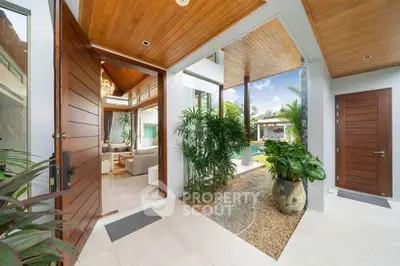 Luxurious open entrance with wooden accents and lush greenery leading to a modern living area.