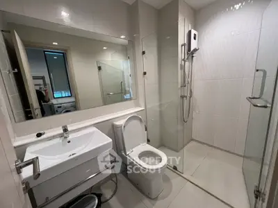 Modern bathroom with glass shower and sleek fixtures in contemporary apartment.