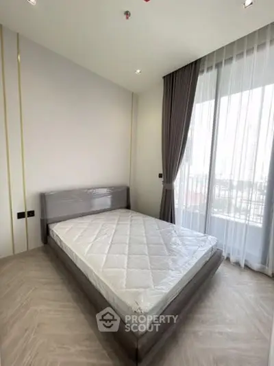 Modern bedroom with large window and elegant curtains in a stylish apartment.