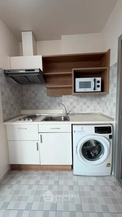 Modern compact kitchen with washing machine and microwave, ideal for urban living.