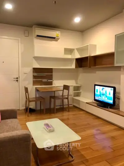 Modern living room with wooden flooring, stylish furniture, and wall-mounted TV.
