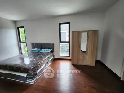 Spacious bedroom with hardwood floors and modern furniture in a bright, airy setting.