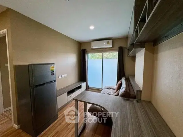 Modern living room with sleek furniture and large window, featuring a compact fridge and air conditioning.