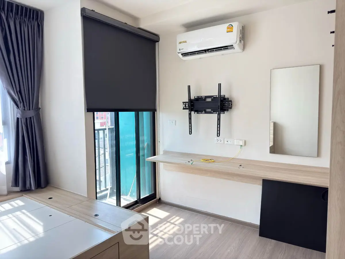 Modern room with air conditioning and balcony access, featuring sleek furniture and natural light.