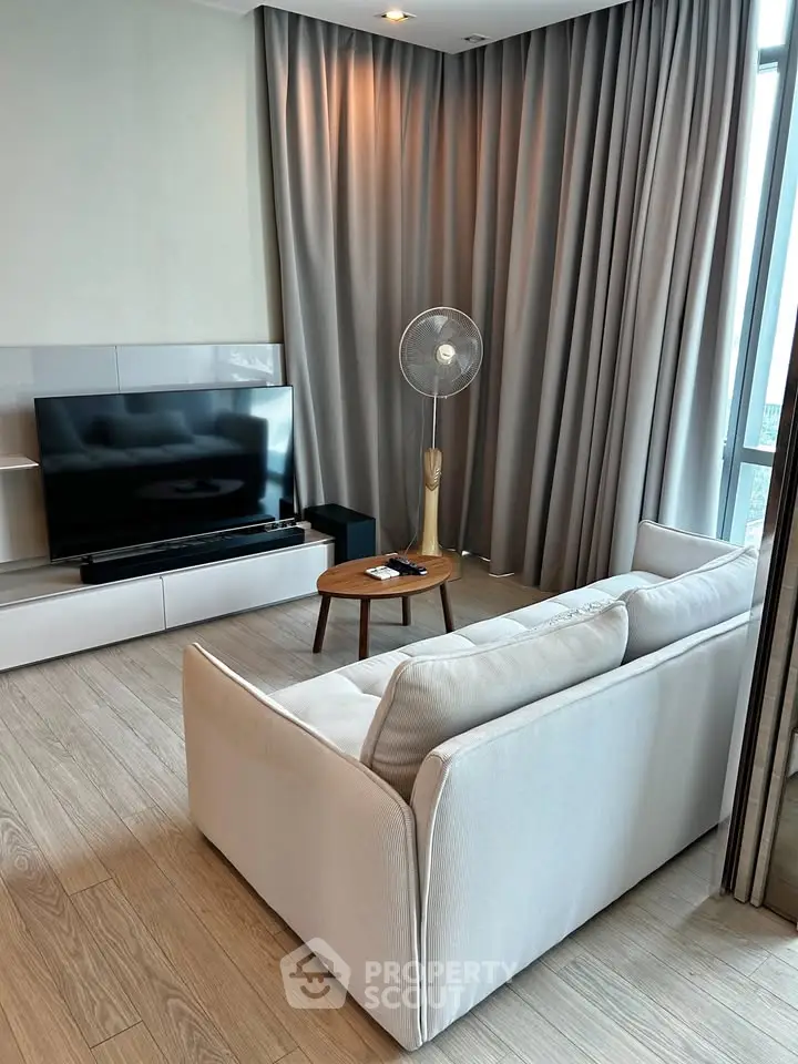 Modern living room with sleek TV setup and elegant curtains in a cozy apartment.