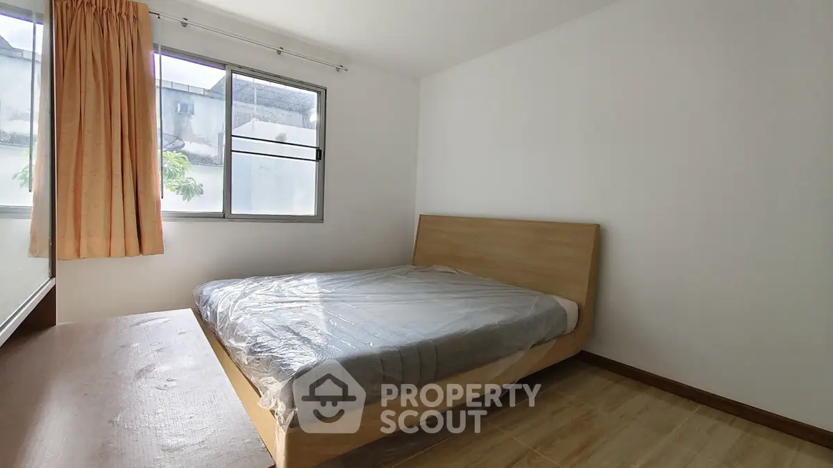 Spacious bedroom with natural light and modern wooden bed frame.
