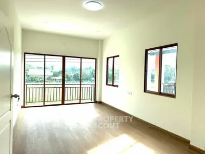 Bright empty room with large windows and balcony view, perfect for customization.