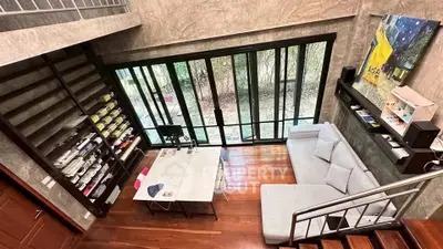 Modern loft-style living room with large windows and cozy seating area.