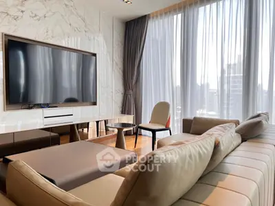 Luxurious living room with modern decor and large TV, featuring floor-to-ceiling windows with city view.
