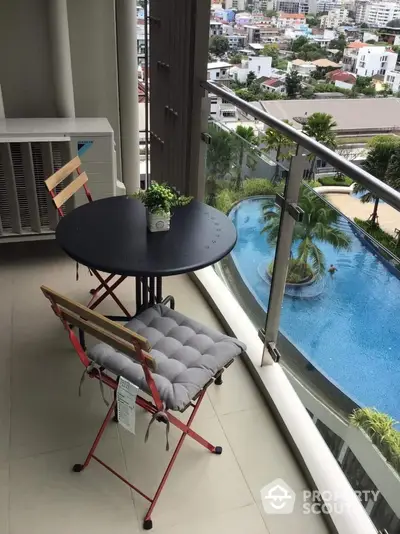 Charming balcony with pool view and cozy seating in modern apartment.