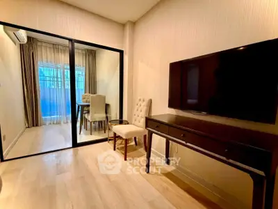 Modern living room with sleek TV setup and elegant glass partition leading to a cozy dining area.