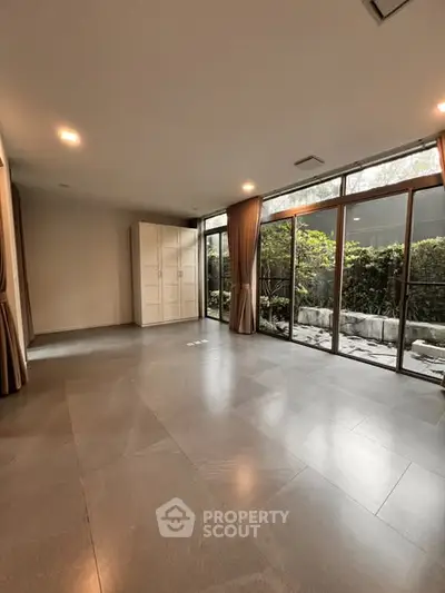 Spacious living room with large windows and garden view, perfect for natural light lovers.