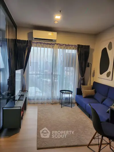 Modern living room with blue sofa, large window, and stylish decor in a cozy apartment.